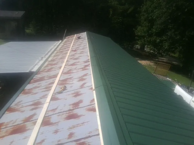 Old rusted panels beside newly installed green metal roofing — Wind Damage Roof Repair by Roofing Brothers in Melcher Dallas