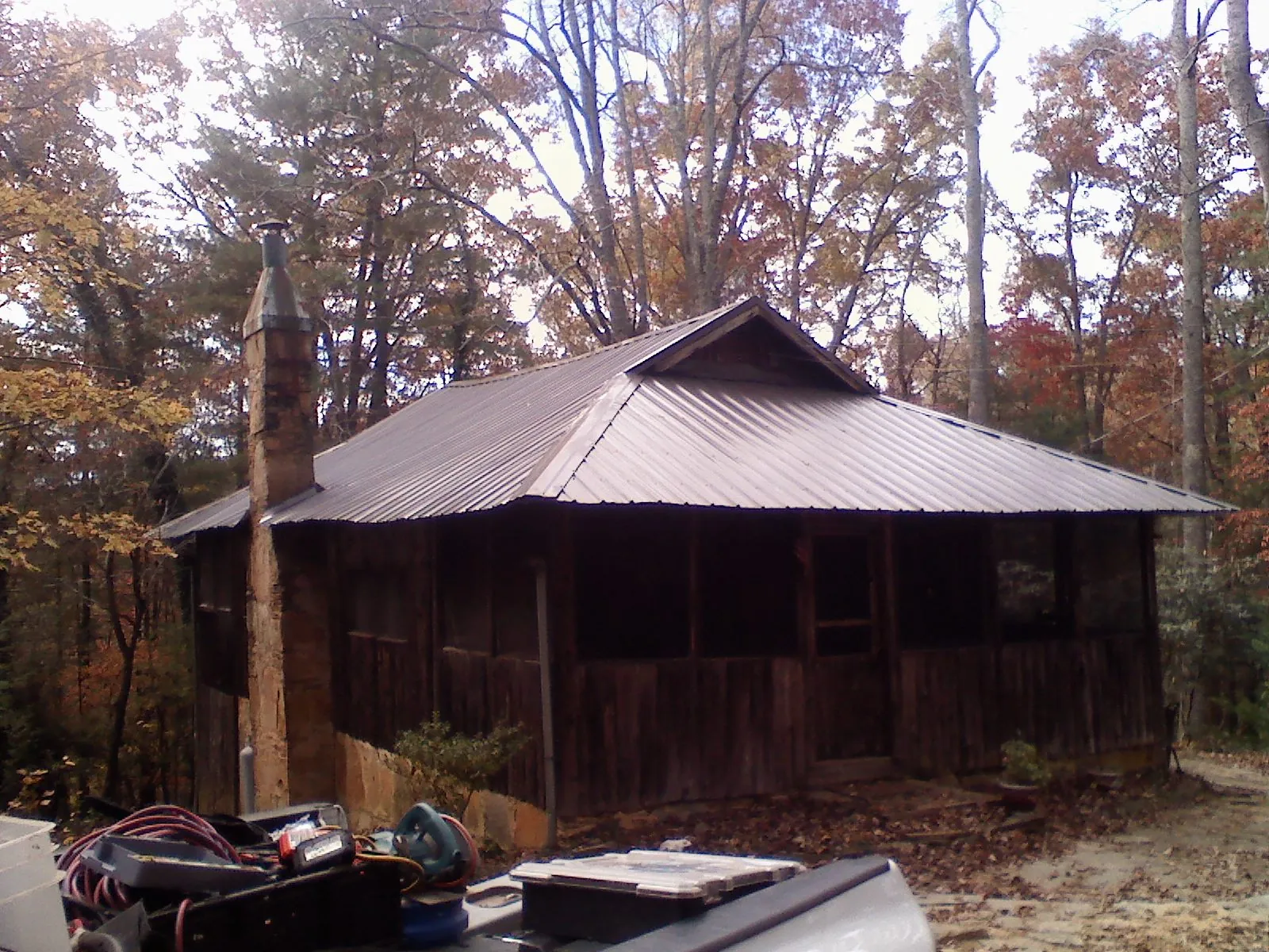 Brown metal hip roof on an old cabin with a stone chimney in Melcher Dallas