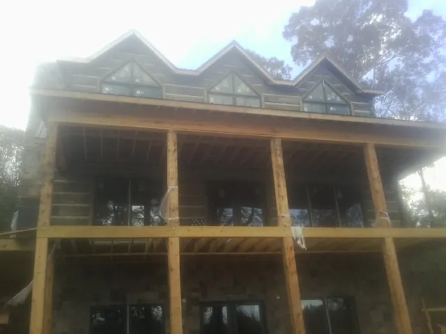 Dormers and porch framing on a large log home under construction — Roof Coating work by our crew in Melcher Dallas