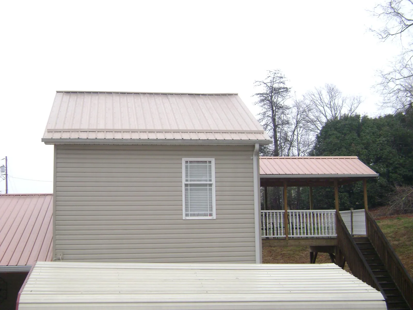 Tan metal roofs on a two story addition and attached porch, from a Roof Replacement job in Melcher Dallas