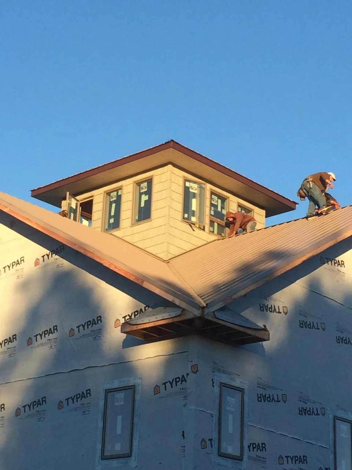 Roofers working around a rooftop cupola on a new metal roof at sunset — Roof Waterproofing in Melcher Dallas by Roofing Brothers
